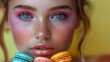 Fashion model with colorful make-up and manicure taking colorful macaroons. Beautiful woman, bright make-up. Purple lipstick, vivid eyeshadow, and accessories. Diet and dieting concept. Sweets.