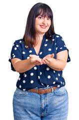 Poster - Young plus size woman wearing casual clothes smiling with hands palms together receiving or giving gesture. hold and protection