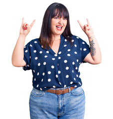 Poster - Young plus size woman wearing casual clothes shouting with crazy expression doing rock symbol with hands up. music star. heavy music concept.