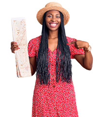 Poster - Young african american woman wearing summer hat holding city map pointing finger to one self smiling happy and proud