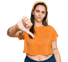 Wall Mural - Young hispanic woman wearing casual clothes looking unhappy and angry showing rejection and negative with thumbs down gesture. bad expression.