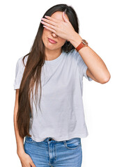 Sticker - Young hispanic girl wearing casual white t shirt covering eyes with hand, looking serious and sad. sightless, hiding and rejection concept