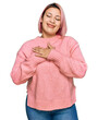 © Krakenimages.com - Hispanic woman with pink hair wearing casual winter sweater smiling with hands on chest with closed eyes and grateful gesture on face. health concept.