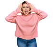 © Krakenimages.com - Hispanic woman with pink hair wearing casual winter sweater smiling cheerful playing peek a boo with hands showing face. surprised and exited