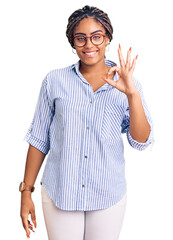 Wall Mural - Young african american woman with braids wearing casual clothes and glasses smiling positive doing ok sign with hand and fingers. successful expression.
