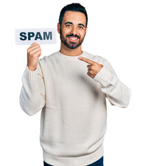 Sticker - Young hispanic man with beard holding spam banner smiling happy pointing with hand and finger