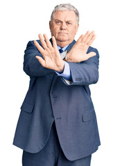 Poster - Senior grey-haired man wearing business jacket rejection expression crossing arms and palms doing negative sign, angry face