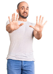 Canvas Print - Young handsome man wearing casual t shirt afraid and terrified with fear expression stop gesture with hands, shouting in shock. panic concept.