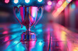 A silver trophy cup in colorful holographic lighting with bokeh and with copy space.