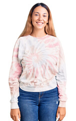 Poster - Beautiful young woman wearing casual tie dye sweatshirt looking positive and happy standing and smiling with a confident smile showing teeth