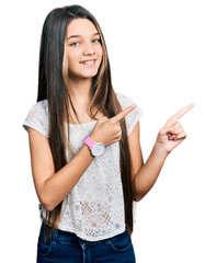 Canvas Print - Young brunette girl with long hair wearing white shirt smiling and looking at the camera pointing with two hands and fingers to the side.