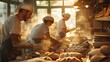 A group of bakers each with a different task work together in the bustling kitchen of a local bakery. The early morning sun streams through the windows illuminating their faces as .