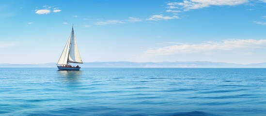 Poster - Sailboat peacefully sails on open sea with majestic mountains in the distance