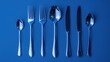 Set of clean silverware is neatly arranged on blue background