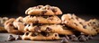 Chocolate chip cookies piled high on a wooden table, surrounded by scattered chocolate chips