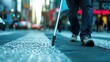 Close-up of person's lower legs walking with white cane on city street blurred background
