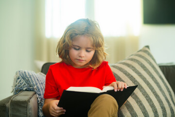 Aufkleber - Concept of education, childhood, book reading, , artwork, inspiration. Child reading book at home. Little boy sitting on couch in living room reading story book. Kid doing homework for school.