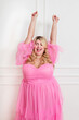 Happy curvy lady wearing pink elegant dress