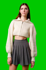 Wall Mural - Young Woman Posing in Stylish Crop Hoodie and Pleated Skirt Against Green Screen