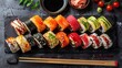 Assorted sushi set on black stone with ginger and soy sauce on dark background
