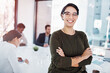 © peopleimages.com - Portrait, professional woman and happy at desk for leadership, motivation and startup company. Pride, planning and management in workplace for career, staff and businesswoman with glasses in office.