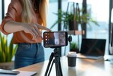 Fototapeta Nowy Jork - A woman's hand is pointing at the phone on top of an tripod