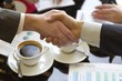 Businessmen shaking hands over coffee