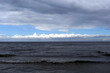 Dark cold waves of the Baltic Sea with layer of white clouds on skyline on a overcast windy day
