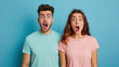 Photo of beautiful couple man and woman in basic clothing screaming in surprise on pastel blue background