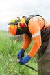 © ADDICTIVE STOCK - Worker sharpening a scythe in the field