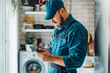 © VisualProduction - Man plumber work in uniform indoors using mobile phone.