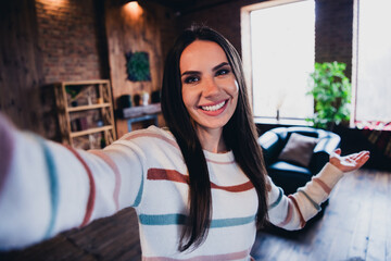 Sticker - Photo of lovely young woman take selfie photo hand point empty space wear striped outfit interior home living room in brown warm color