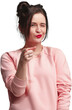 © master1305 - Woman with hair bun, winking and pointing, wearing pink sweatshirt isolated on transparent background. Friendly positive expression. Concept of human emotions, facial expression.