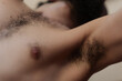 Closeup of a bearded man's upper body, showing his chest hair, underarm hair, nipple, and beard. The shallow depth of field leaves his face anonymous.