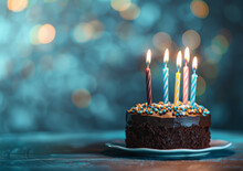 A Chocolate Birthday Cake With Colorful Candles On Blue Bokeh Background, Copy Space For Text