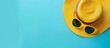 © Bambalino Studio - A yellow straw hat with sunglasses on top of it. The hat is on a blue background. The hat and sunglasses give a sense of summer and relaxation