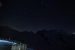 Serene night sky over Zermatt ski resort in the Swiss Alps. Starry night, mountain silhouette, fenced off area, lights, metal containers. Majestic alpine beauty and peacefulness.
