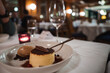 Elegant dessert presentation on white plate with flan, cocoa, chocolate garnish, ice cream, berries in luxury hotel dining room in Zermatt, Switzerland.