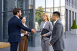 © Liubomir - Interracial group of young business people standing on street outside office building in suits, man and woman shaking hands, making deal and getting to know partners and clients.
