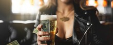 Front View Of Young Woman Holding Glass Of Beer At Bar