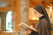 Portrait of Caucasian nun reading bible book in the church