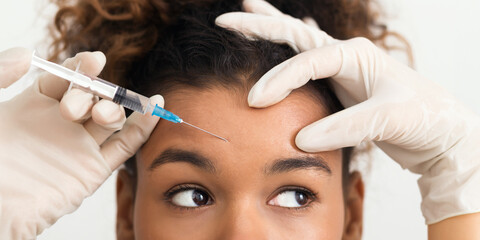 Wall Mural - African-american woman getting botox injection in forehead