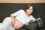 Fototapeta  - Expectant mother looking at sonograms on couch