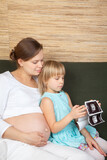 Fototapeta  - Expectant Mother and Daughter Looking at Ultrasound