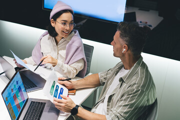 Fototapete - Happy male and female partners with digital laptops communicate about business trade during brainstorming in office, successful graphic designers analyzing report documents and marketing
