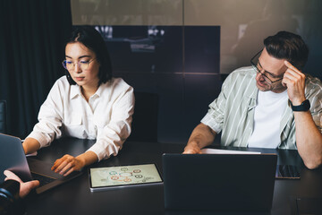 Fototapete - Male and female colleagues in optical eyeglasses for provide vision protection using netbook computers for creating UI UX product design in teamwork, skilled entrepreneurs cooperate on startup