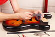 Guitar repairer measures body of guitar with caliper.