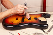Guitar technician measures body of guitar with ruler.