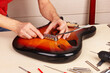 Guitar repairer installs tremolo in guitar body.