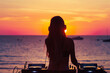 © Vladimir - Silhouette Female DJ at Sunset Beach. Silhouette of female DJ mixing music at sunset on beach.